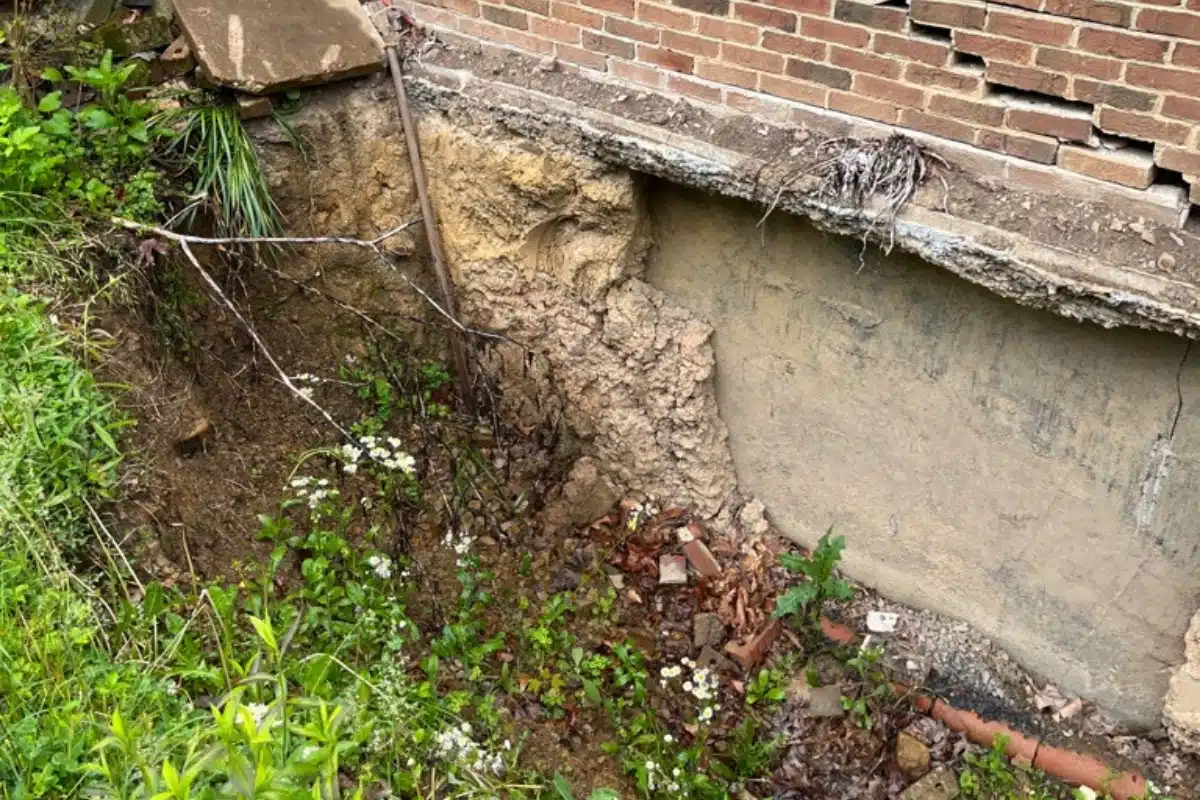 Settled ground near a foundation worsening improper soil grading in Gainesville, VA that causes crawl space moisture issues.