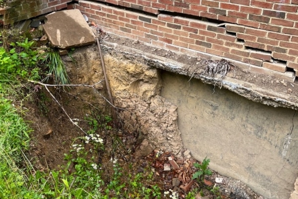 A house with a slope near the basement wall showing poor soil compaction as a cause of foundation damage in Reston, VA.