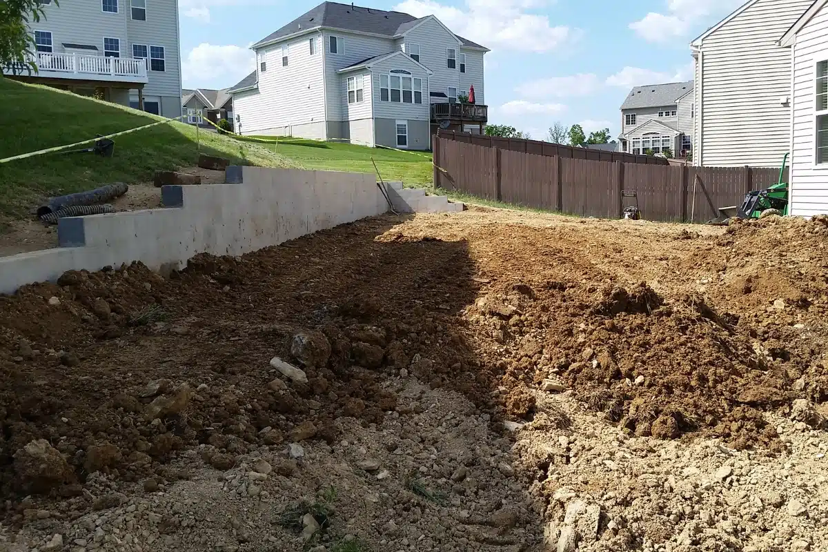 A backyard with soil sloping toward the foundation, illustrating poor soil grading in Brambleton, VA, causing crawl space issues.