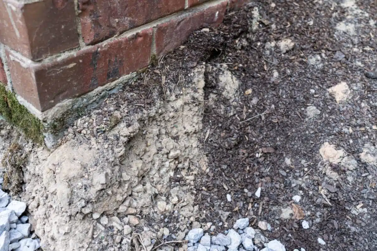 Soil eroding near a home's foundation, showing how erosion over time causes crawl space issues from poor soil grading in Southbridge, VA.