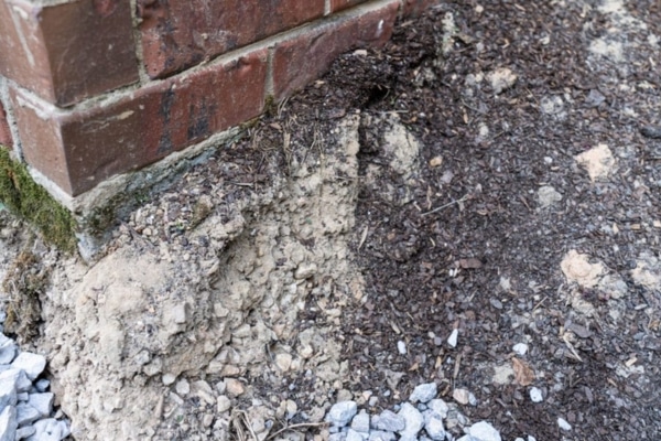 A house with a visible void underneath, showing soil settlement and shifting as causes of foundation damage in Alexandria, VA.