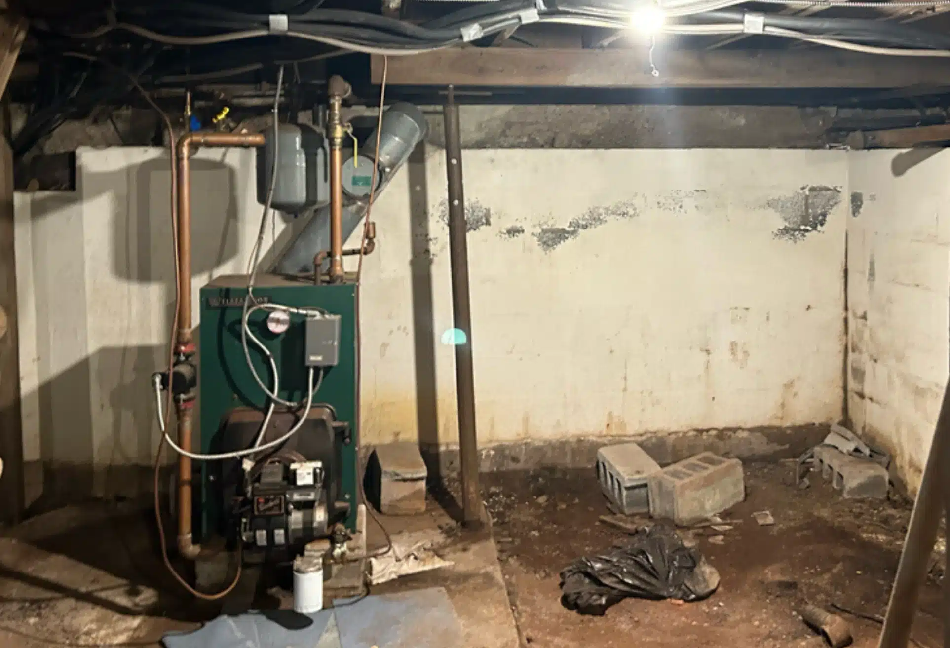 Crawl space with exposed dirt floors, rusted steel supports, and weakened beams before crawl space restoration in Ashburn, VA.