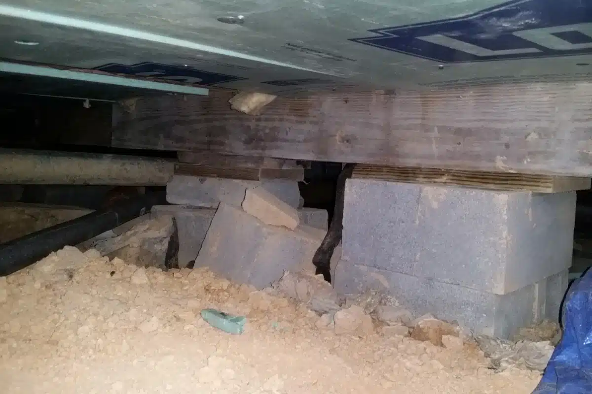 Crawl space floor with damaged cinder block posts, showing inadequate design, causing support system failure in Harpers Ferry, WV.