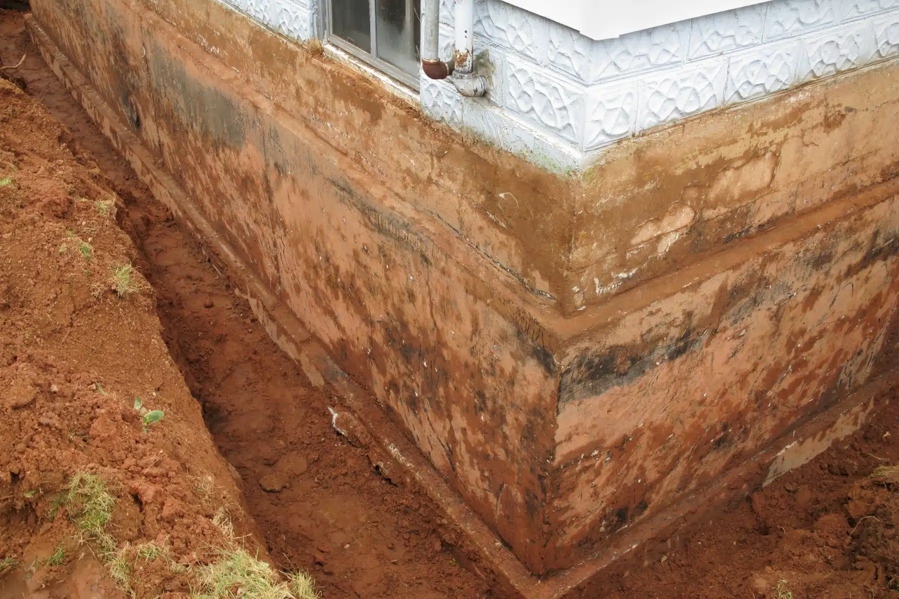 Improper landscape grading near a foundation showing how poor practices cause crawl space issues during heavy rain in Reston, VA.