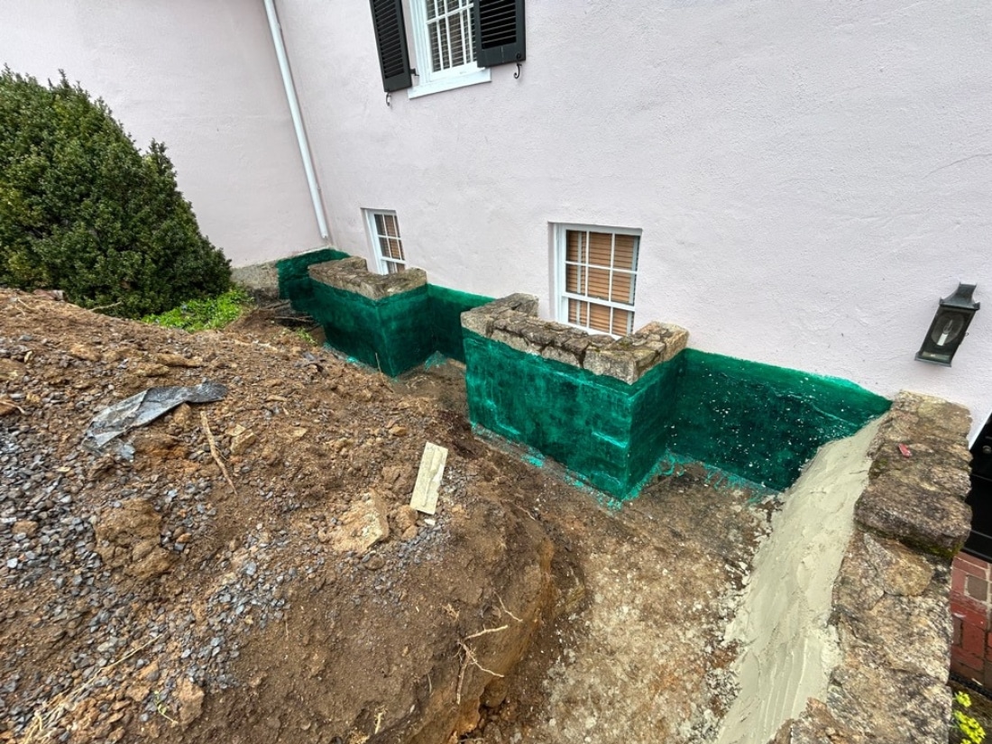 Undermined two deteriorated stone window wells to prepare for structural restoration and exterior waterproofing in Marshall, VA.