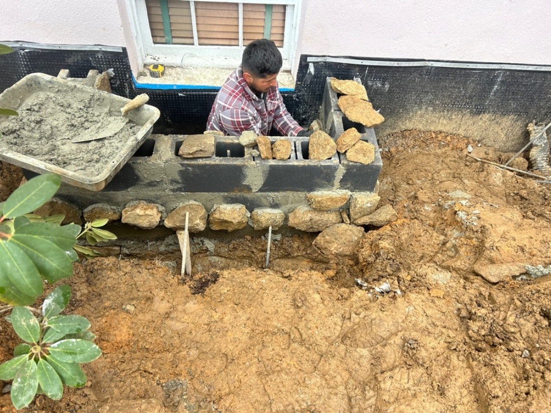 Construction of two stone window wells for ventilation, drainage, and moisture control during exterior waterproofing in Rixeyville, VA .