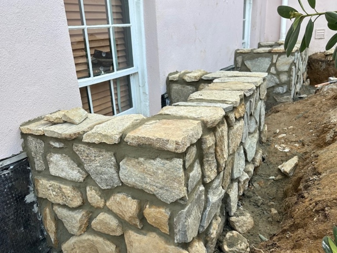 Applied mortar mix to new stone window wells to preserve the home's historic aesthetic during exterior waterproofing in Amissville, VA.