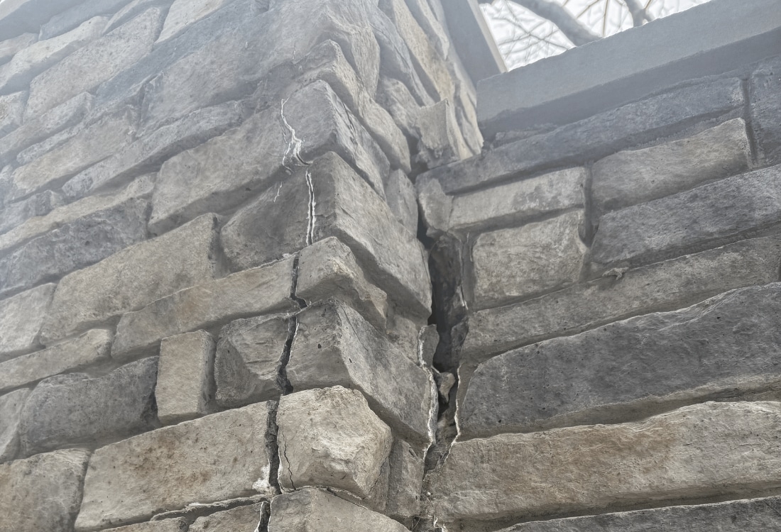 Large cracks forming on a 14-foot residential retaining wall in Alexandria, VA, due to excessive soil pressure.