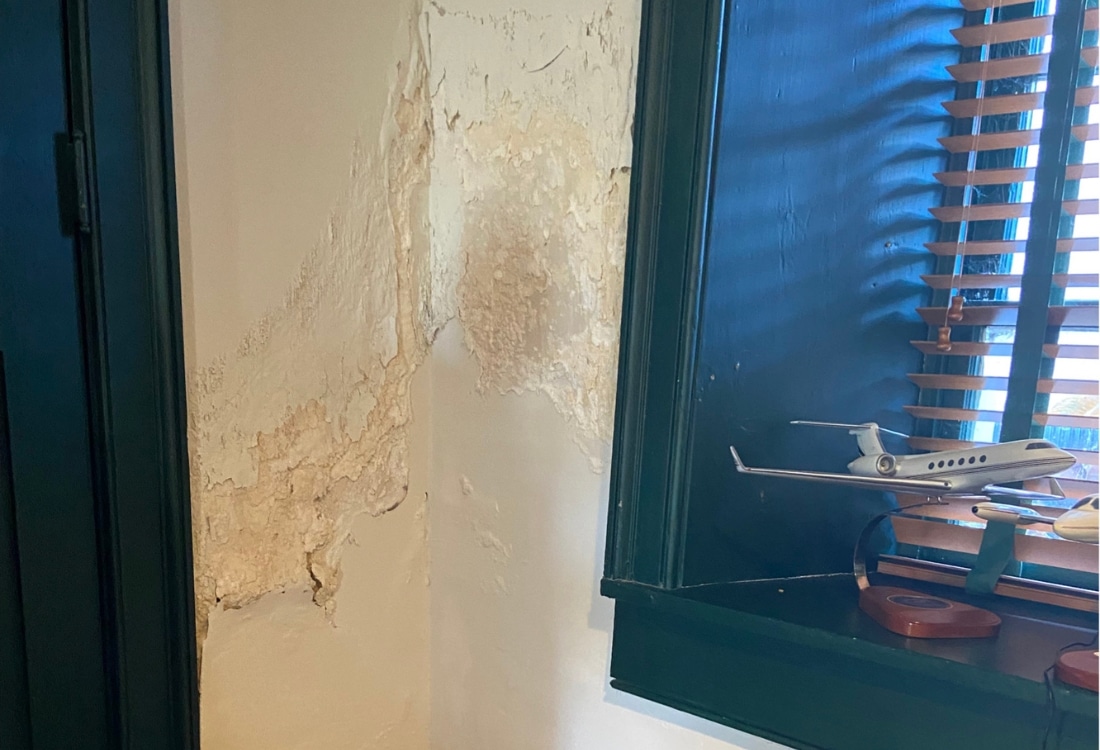 Peeling paint and bubbling foundation drywall of a historic Front Royal, VA home indicates moisture intrusion and poor drainage.