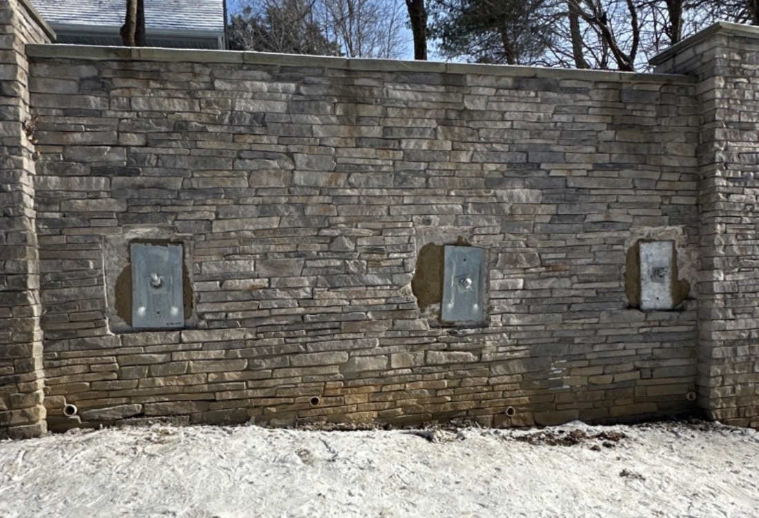 Reinforced retaining wall stabilized with 14 helical tieback anchors to prevent future movement.