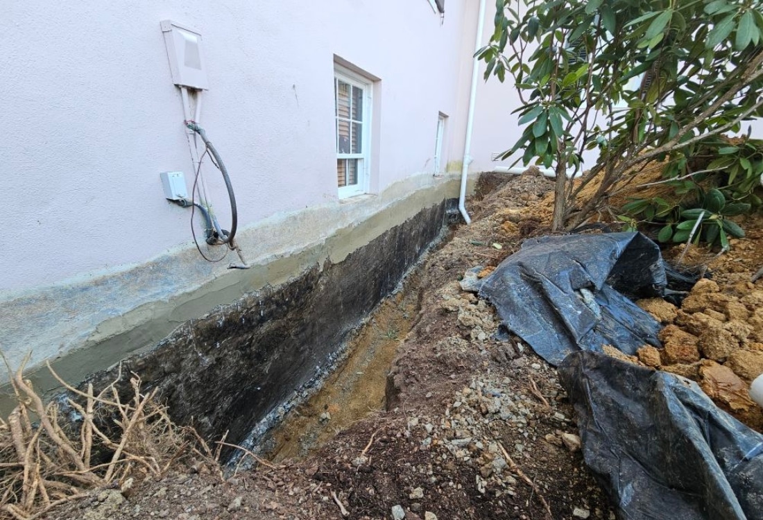 Unwaterproofed exterior foundation wall in Flint Hill, VA, with visible cracks, poor drainage, and moisture damage.