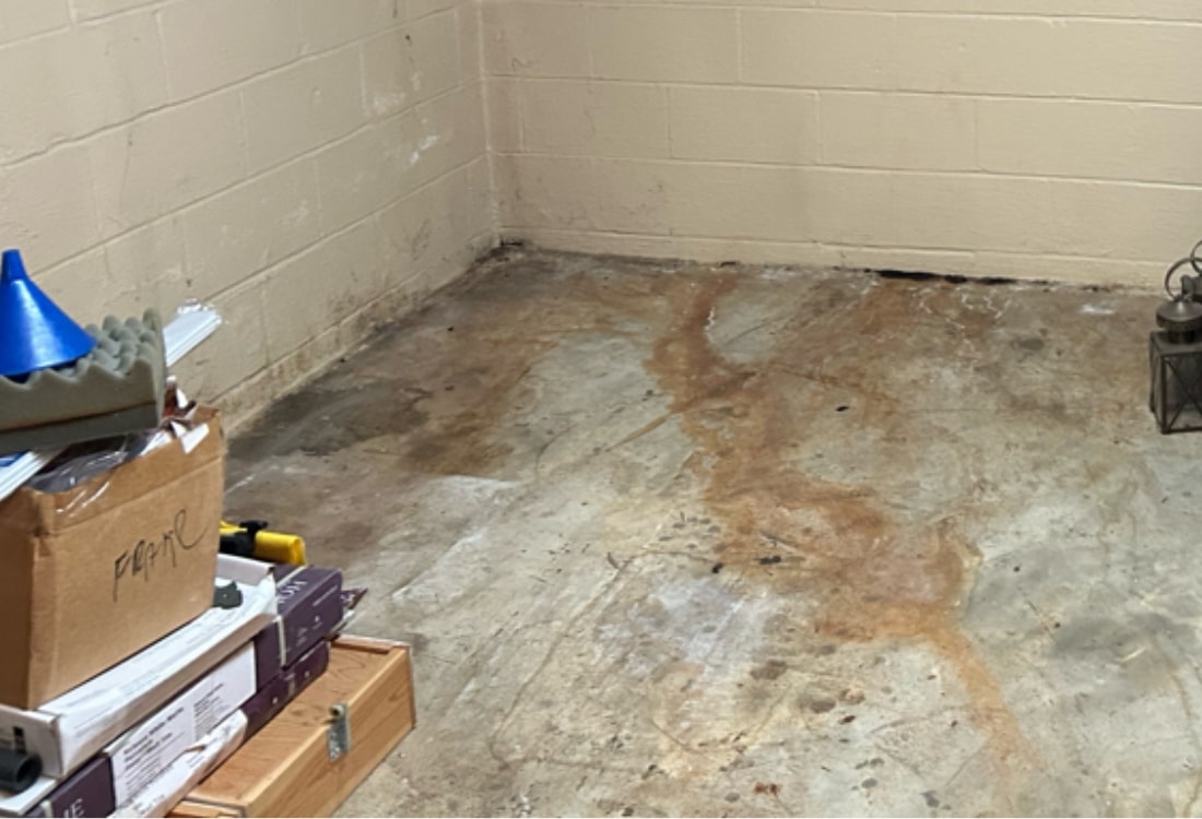 Basement in Berryville, VA, showing water stains and no drainage system, leading to persistent moisture and unusable space.
