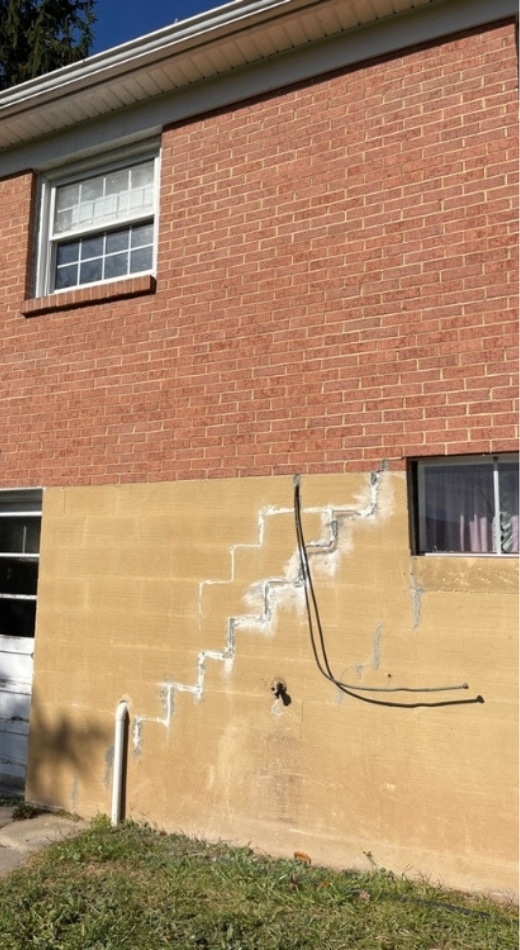 House with wide foundation cracks, the effects of water damage, soil erosion, —common causes of foundation issues in Fairfax, VA.