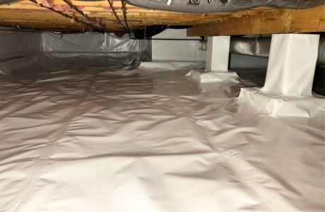 Crawl space encapsulation in Winchester, VA, using a durable vapor barrier to prevent moisture intrusion and mold growth.