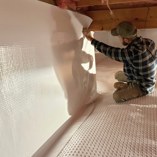 LUX team installing vapor barrier for expert crawl space repair services in Fairfax, VA, preventing moisture damage.
