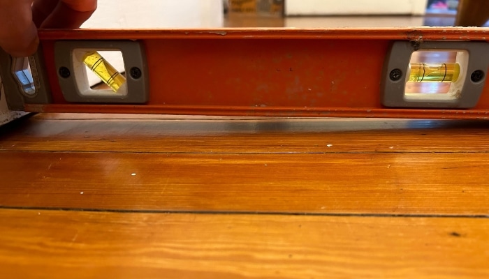 Unlevel floors in Burke, VA, measured with a stick, indicating foundation settlement that requires professional repair for stability.