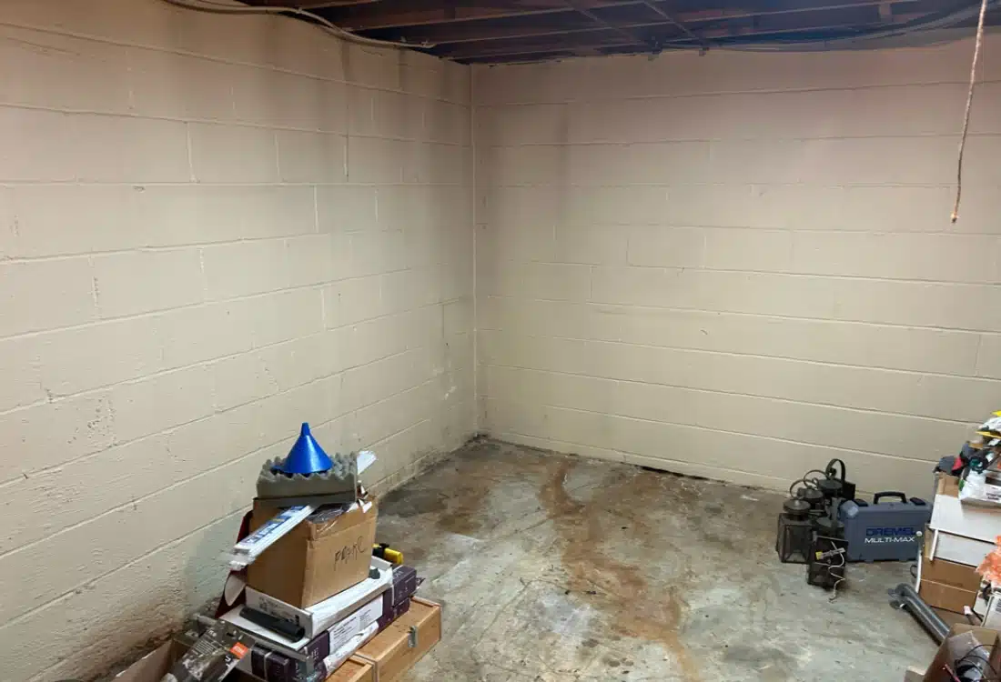 Basement with water stains and musty conditions in Clear Brook, VA, before installing interior drainage and waterproofing system.