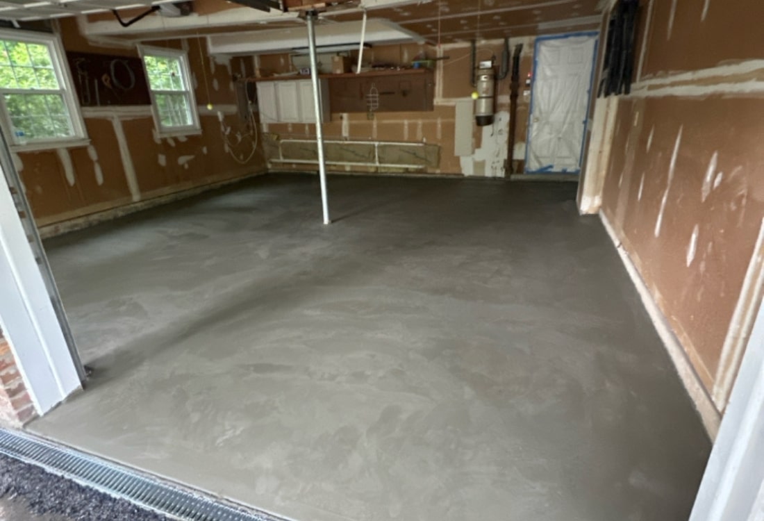Reinforced and level garage concrete floor after full slab replacement in Winchester, VA, with drainage and moisture barrier.
