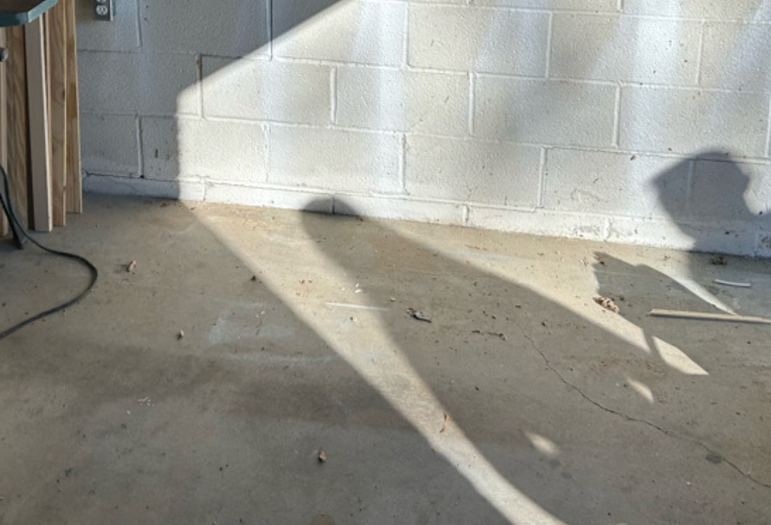 Cracked garage floor and walls before foundation repair in Reston, VA, showing signs of foundation settling and shifting.