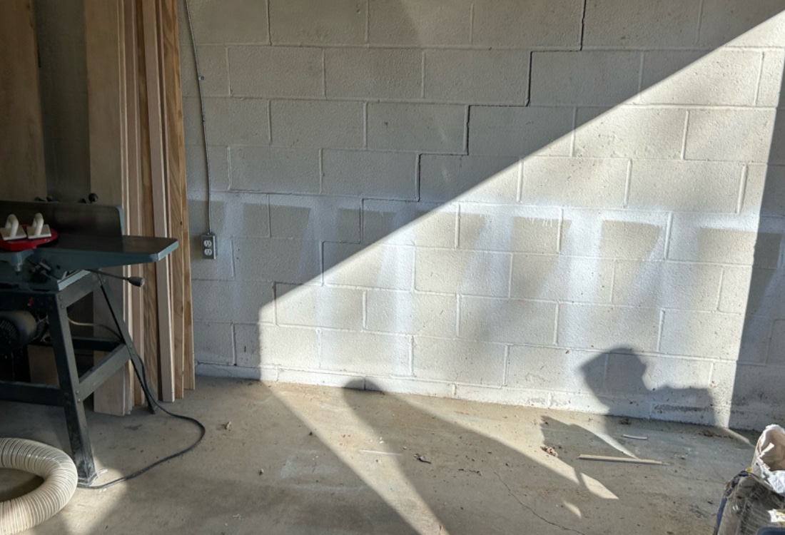 Visible cracks in garage walls and floor from foundation settling in Fairfax, VA, requiring push pier installation for stabilization.