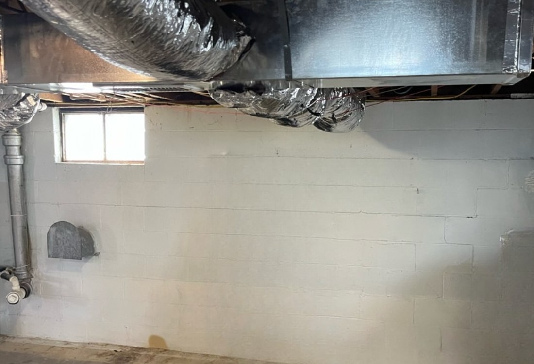 Wall with severe cracks and bowing caused by soil pressure before the basement wall carbon fiber repair in Charles Town, WV.