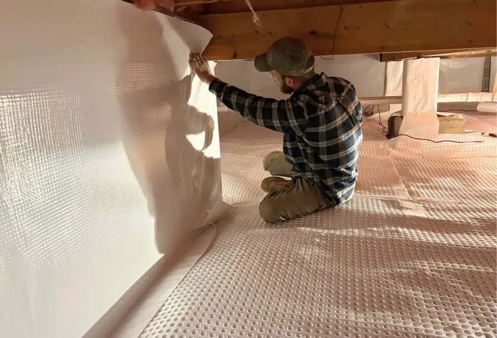 An expert sealing crawl space with a vapor barrier and insulation, a process of crawl space encapsulation in Alexandria, VA.