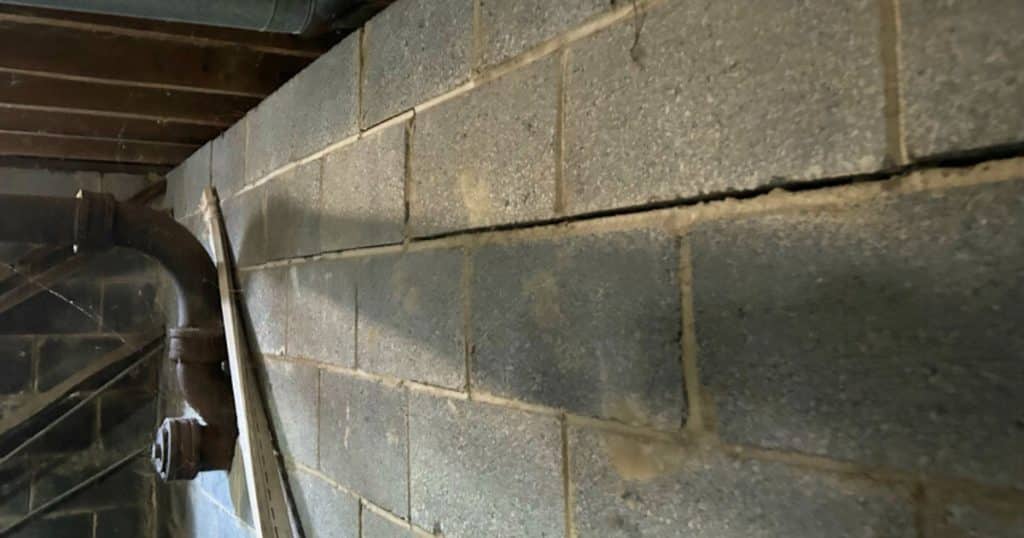 Bowed basement wall showing cracks from hydrostatic pressure before repair in a Northern Virginia home.