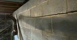 Bowed basement wall showing cracks from hydrostatic pressure before repair in a Northern Virginia home.