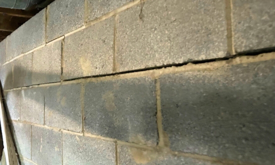 A bowing basement wall, a clear sign of foundation stress requiring repair in Fairfax, VA.