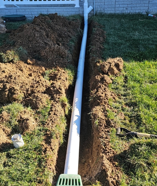 Buried downspout extension installation showing underground drainage pipe directing rainwater from home foundation in White Post, VA.