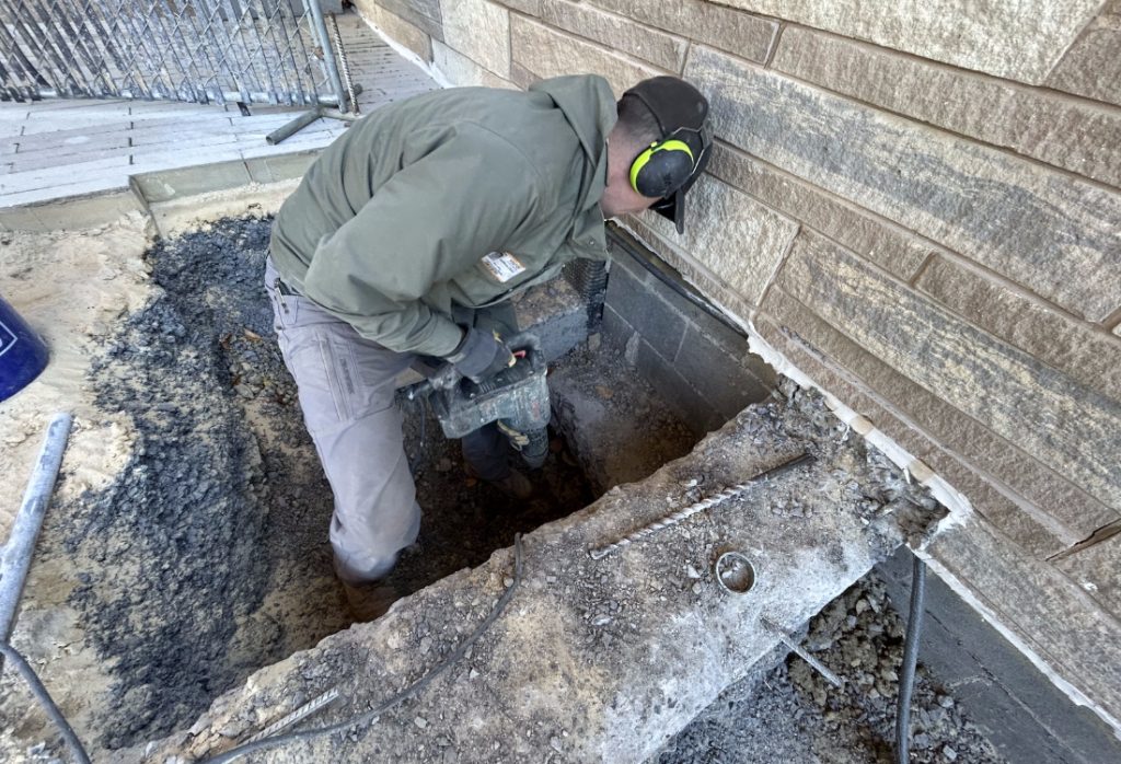 Licensed contractor installing push piers to repair foundation, showing professional home foundation repair services in action.