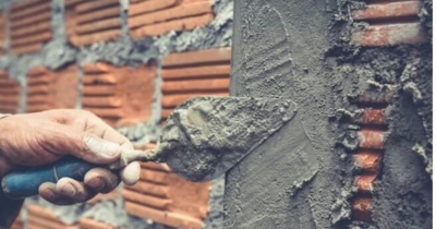 Mason applying cement to a brick wall symbolizing improved structural integrity, an advantage of foundation repair in Flint Hill, VA.