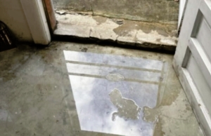 Standing water on a basement floor in Reston, VA, caused by poor drainage and hydrostatic pressure, a sign of basement flooding.