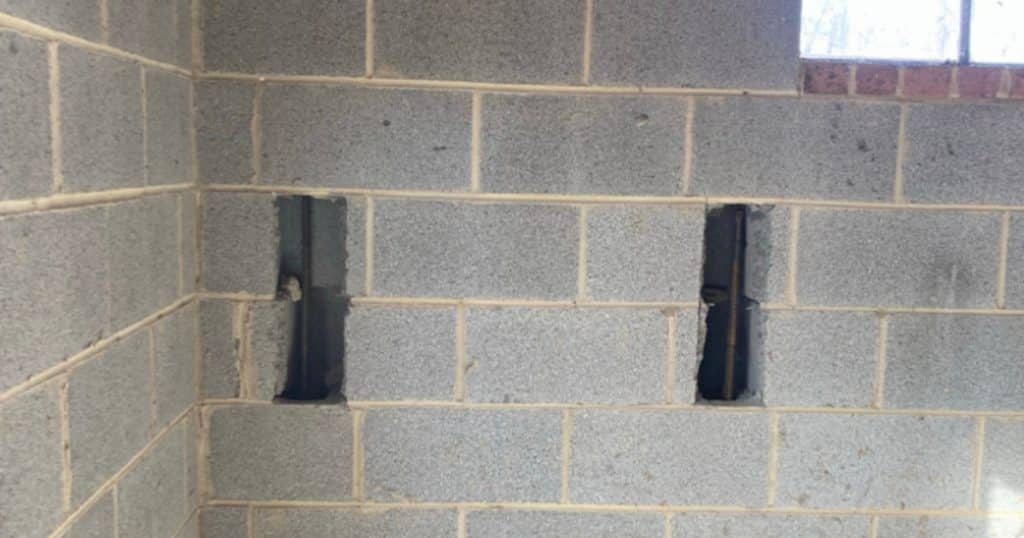 Installed wall rebar pins reinforcing bowed concrete block basement wall in Alexandria, VA, for added stability.
