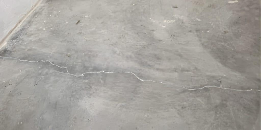 Hairline cracks on a concrete basement slab floor in Northern Virginia, showing normal surface cracking from concrete curing.