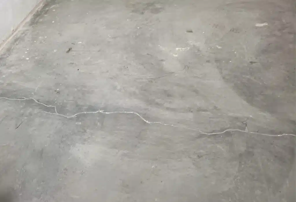 Close-up of thin hairline cracks on a concrete slab floor in Winchester, VA, typical of normal shrinkage after curing.