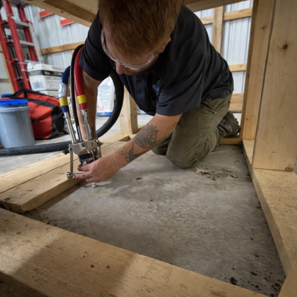 Technician injecting polyurethane to lift and level a sunken concrete slab, a concrete repair solution in Fairfax, VA.