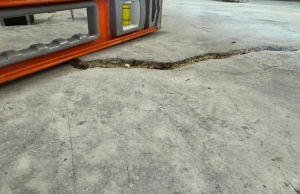 Basement concrete slab crack with level tool showing visible height difference, a sign of a sinking concrete slab in Alexandria, VA.