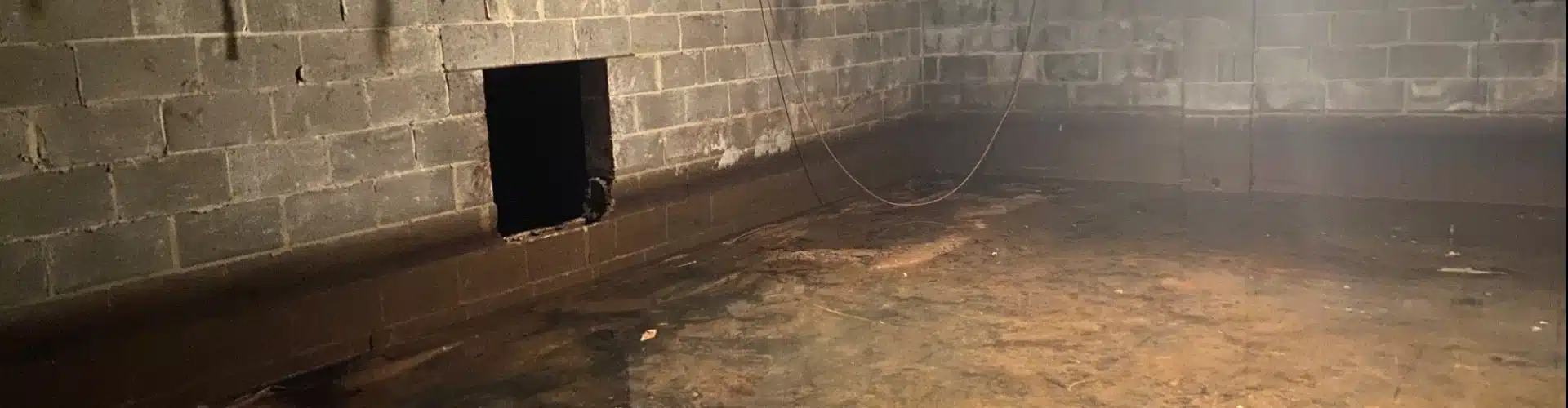 A damp crawl space in Winchester, VA, with visible moisture, showing early signs of crawl space water damage.