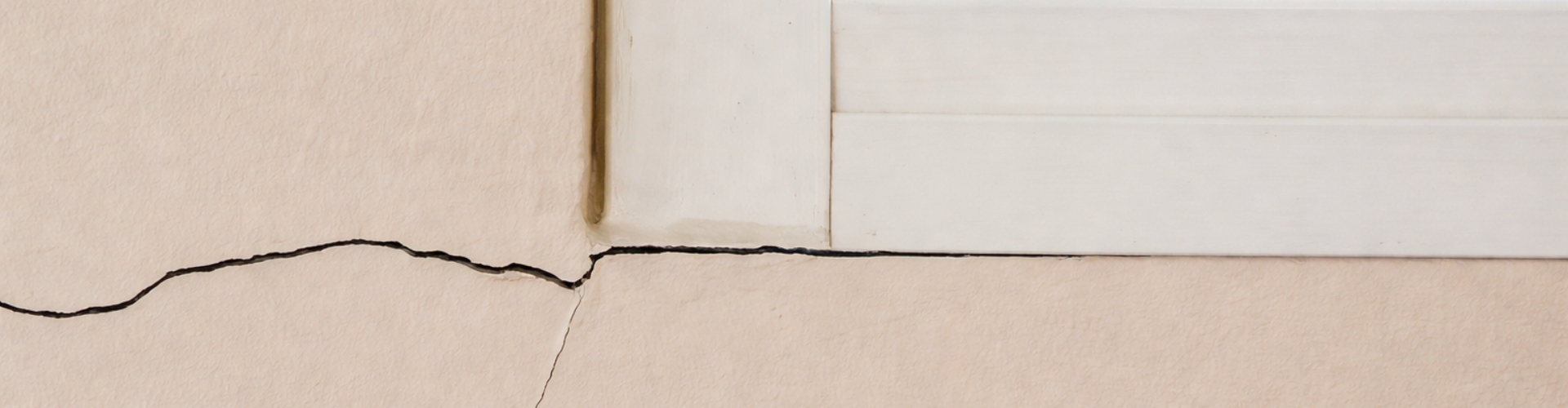 Vertical and horizontal drywall cracks in Northern Virginia below the window, a sign of a foundation problem.