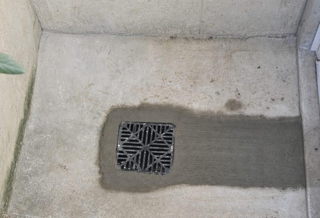 Installed basement floor drain in Winchester, VA, with a metal grate in concrete to manage minor water flow and plumbing moisture issues.