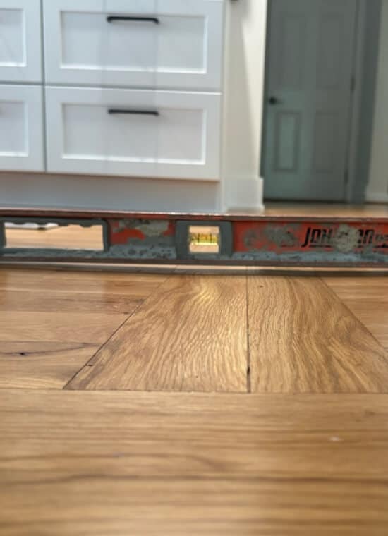 A level tool showing an uneven kitchen floor, a sign of a problem that needs floor sagging above crawl space repair in Northern VA.