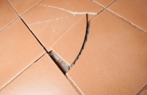 Cracked and lifted floor tiles separating from grout due to slab movement, a sign of a sinking concrete slab in Fairfax, VA.