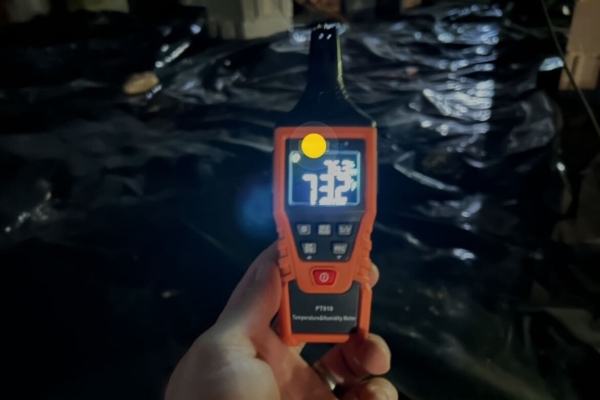 Humidity meter reading high moisture levels in a crawl space with a vapor barrier, indicating crawl space problem in Alexandria, VA.