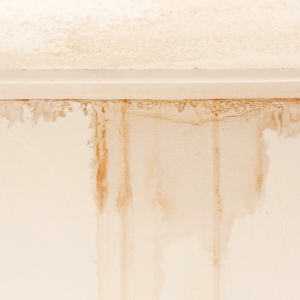 Brown water stains and streaking along wall trim from moisture intrusion, causing drywall cracks in Reston, VA.
