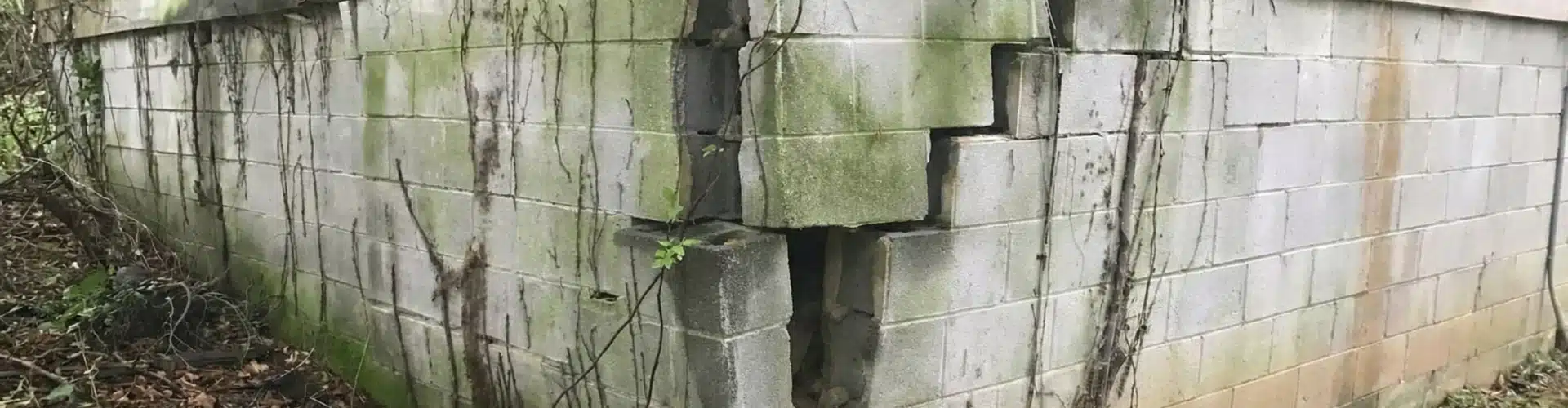Severely bowing and cracked cinder block foundation wall, a sign of a sinking foundation in Winchester, VA.
