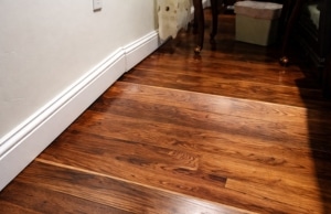 Visibly sloped hardwood floor with uneven surface along baseboard, signs of sinking foundation in Martinsburg, WV.