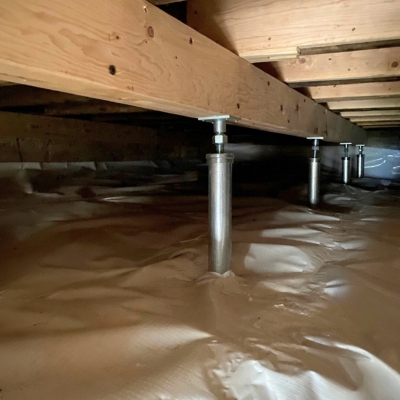 Installed steel stabilizer posts supporting floor joists in crawl space to reduce sagging and repair drywall cracks in Southbridge, VA.