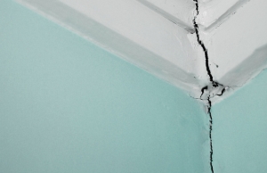 Long vertical drywall crack splitting from ceiling corner down wall seam, a sign of drywall cracks in Alexandria, VA.