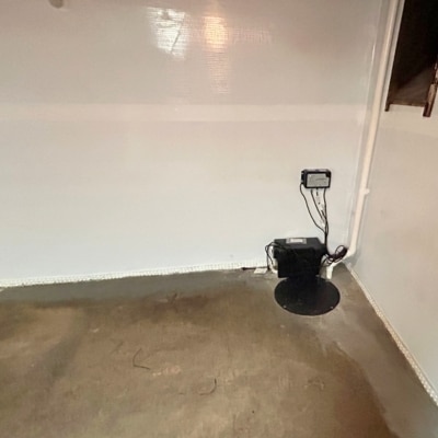 Installed sump pump in a basement pit, collecting groundwater from the surrounding foundation to prevent wall seepage.